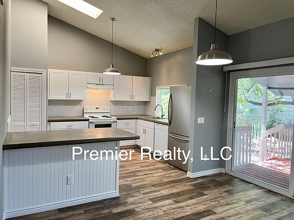 Open eat-in kitchen has been updated with concrete counters, white cabinets, and tile backsplash.