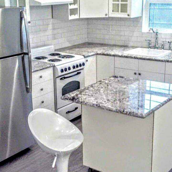Granite Countertops with stainless fridge small island on wheels to create more space if needed. White and brite cabinets !