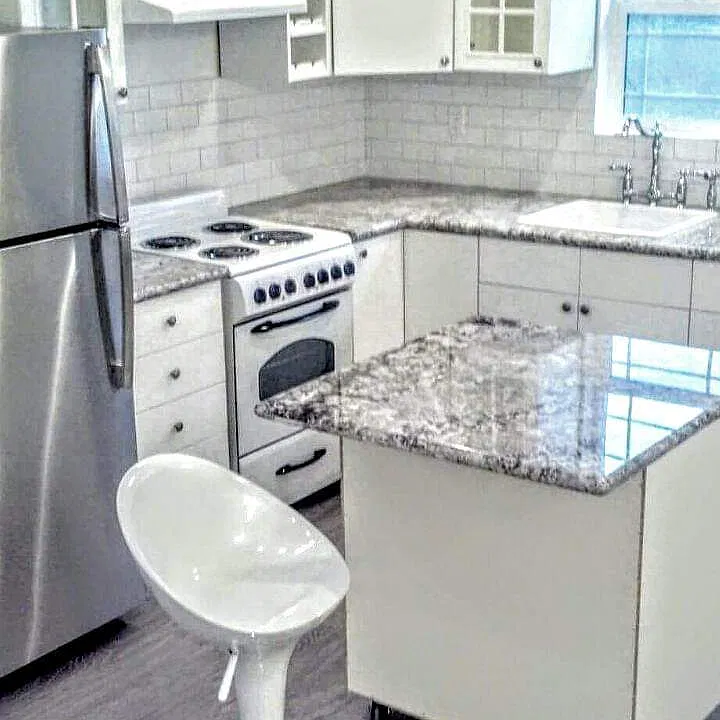 Granite Countertops with stainless fridge small island on wheels to create more space if needed. White and brite cabinets !