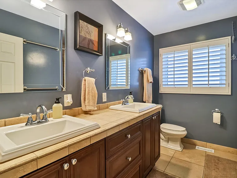 Main bathroom (located between main bedroom and second bedroom) includes dual sinks and original porcelain bathtub with Travertine tile that extends from tub to ceiling.