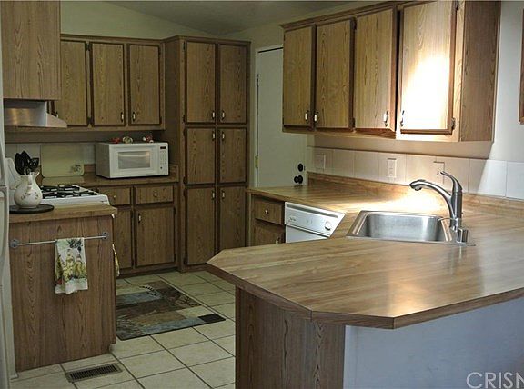 Spacious kitchen has dishwasher, refrigerator, microwave, stove, farmhouse style stainless sink