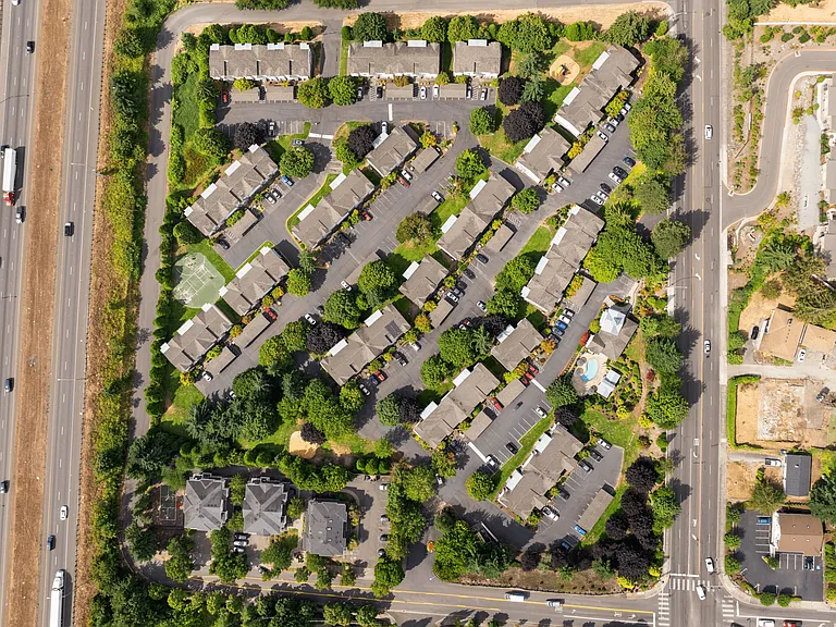 Bird's-eye view of the apartment community highlighting the layout, landscaping, and proximity to major roads.