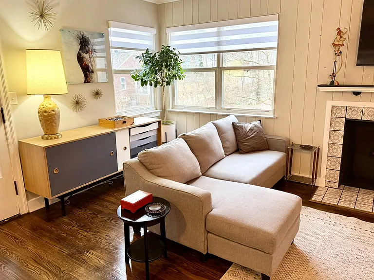 Living room, sleeper couch and mid-mod inspired console filled with books, games and puzzles