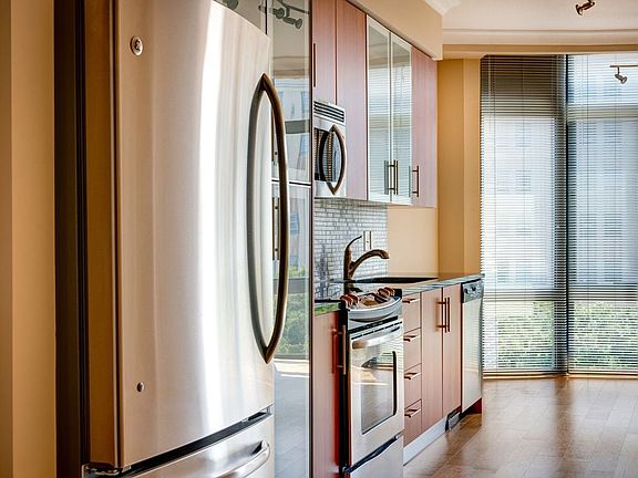 Kitchen with granite countertop, stainless steel appliances, designer backsplash, hard surface flooring and floor to ceiling windows