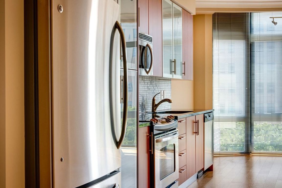 Kitchen with granite countertop, stainless steel appliances, designer backsplash, hard surface flooring and floor to ceiling windows