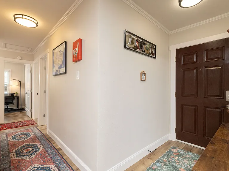 Private front entrance opens into a bright hallway with stylish rugs and decor, connecting all bedrooms and living spaces for easy access and a welcoming first impression.