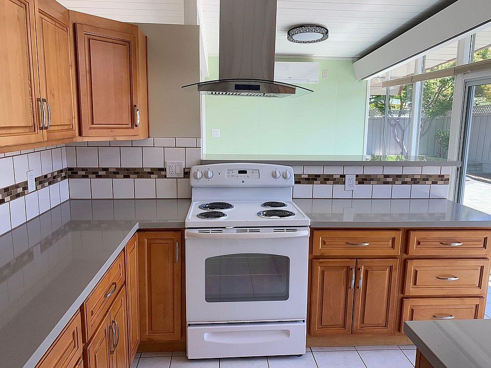 Kitchen with quartz countertop, ceramic tile backsplash, electric range and oven.