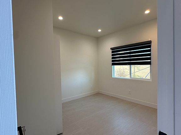 Bedroom 1 _ Bright and spacious with 9-foot ceilings, modern flooring, recessed lighting, and a large window. Includes a built-in closet with double hanging racks for added storage and smart-home comfort.