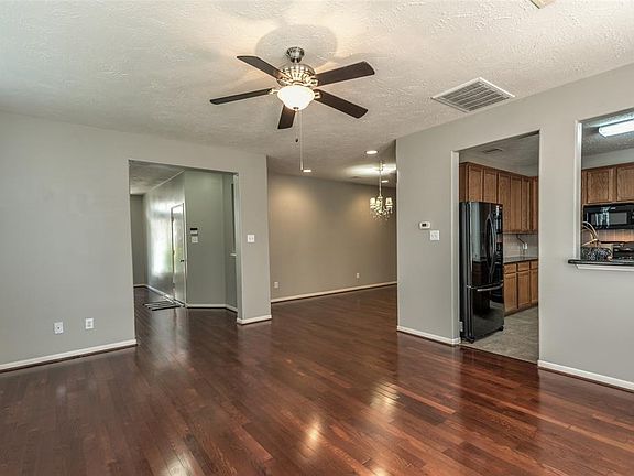 Open floor plan with living room, separate dining room all with laminate floors, ceiling fan, center light in dining and open to kitchen.