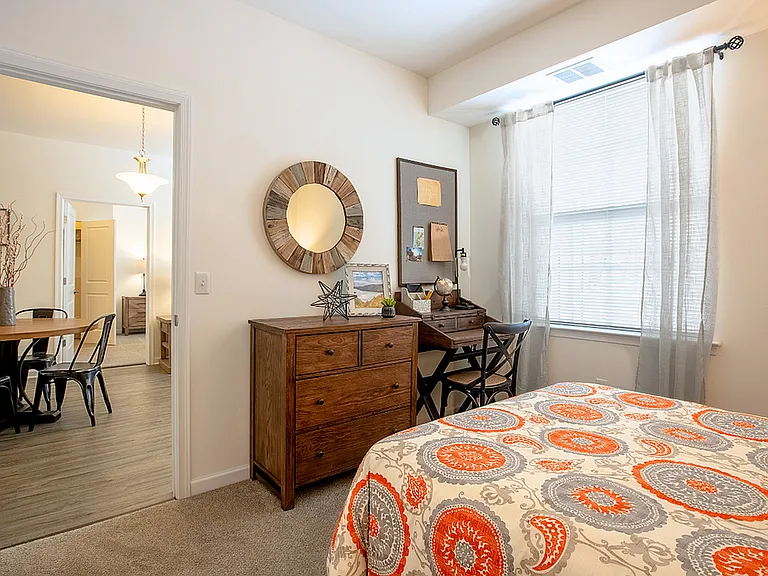 Spacious bedroom in a modern apartment featuring luxury carpeting, ample natural light, and a sleek, contemporary design for a comfortable and stylish retreat.