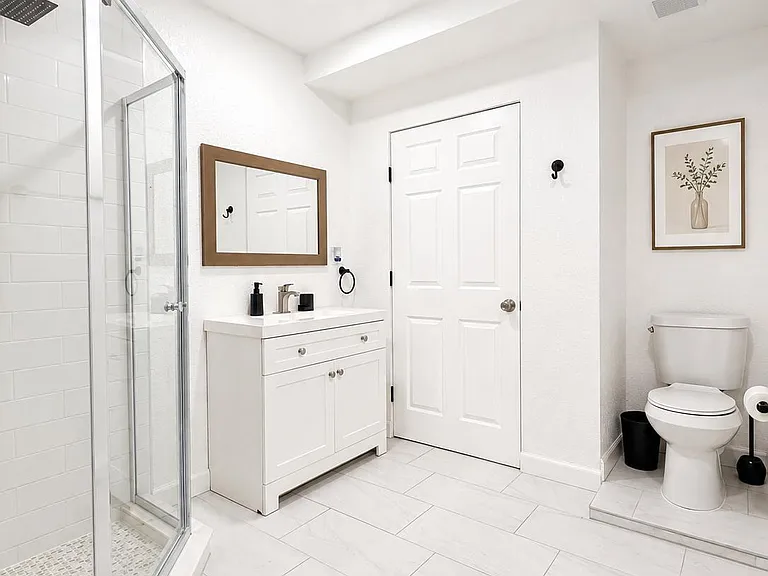 Spacious bathroom with a glass-enclosed shower, large vanity with storage, and tile flooring for easy upkeep.