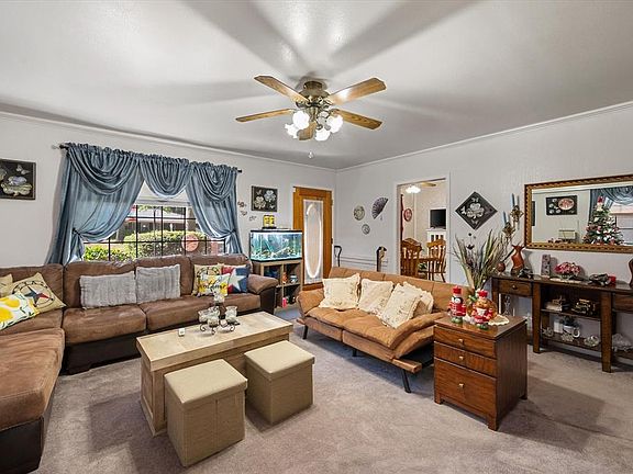 Living room with carpet floors, ornamental molding, and a ceiling fan