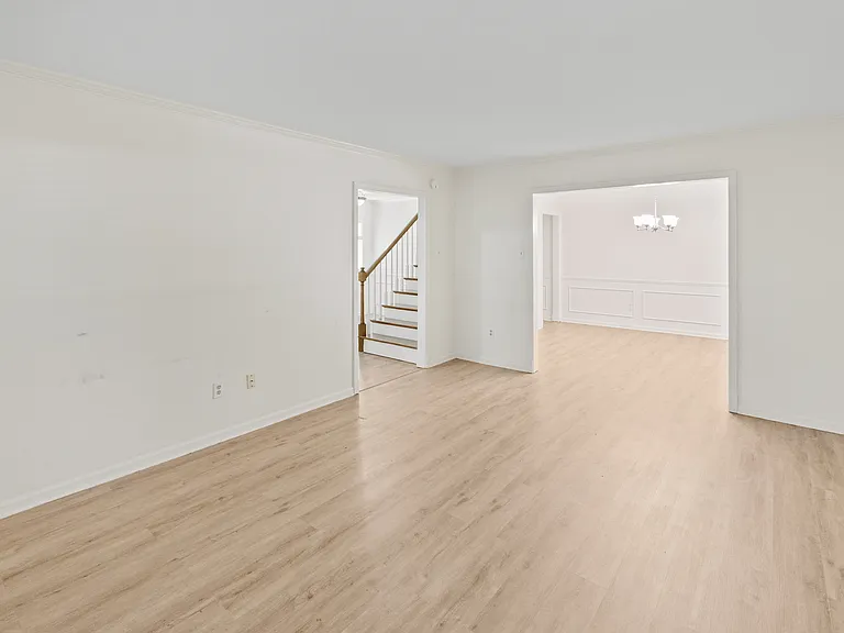 Expansive living area with open flow to the staircase and chandelier-lit dining room _ designed for easy living.