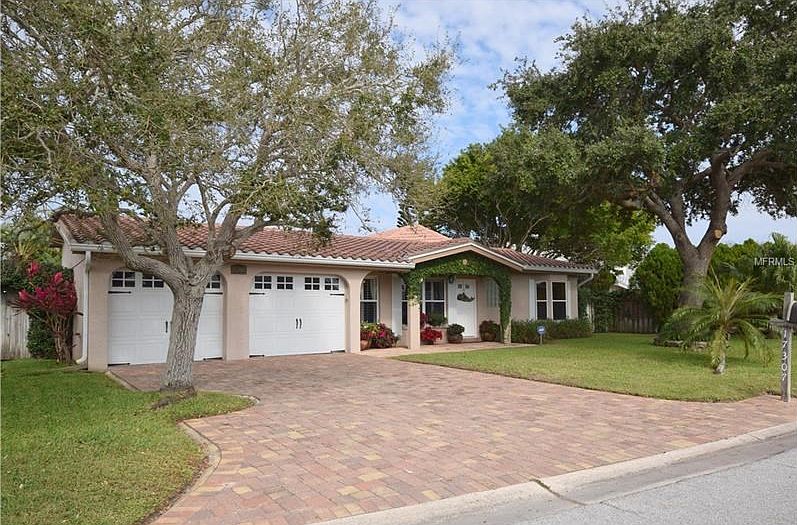 Large pie shaped lot with pavered drivewa, tile roof,  and mature landscaping.