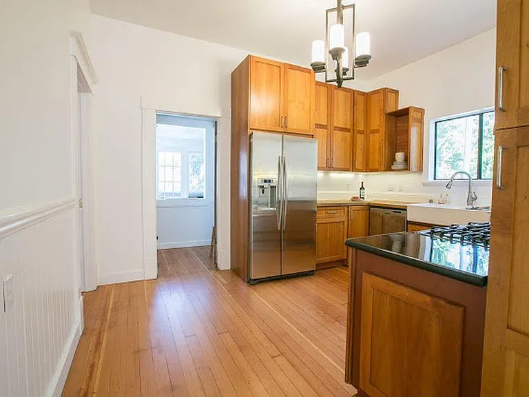 Kitchen with French country sink, under counter lighting, stainless appliances, tall cabinets with plenty of storage. Doorway leading to laundry room and back porch.