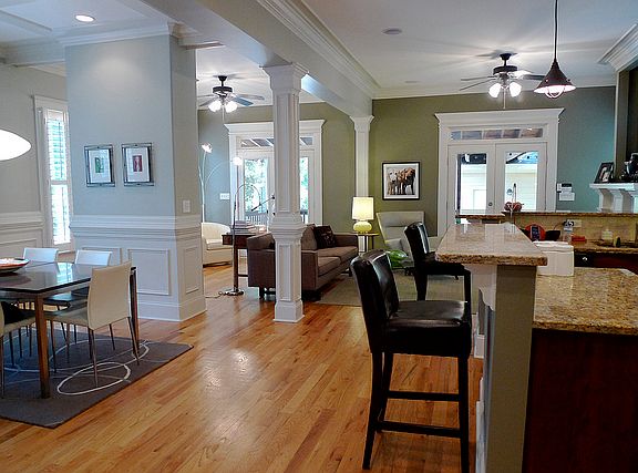Open living area with hardwoods, crown molding, plantation shutters, and french doors leading to the back
