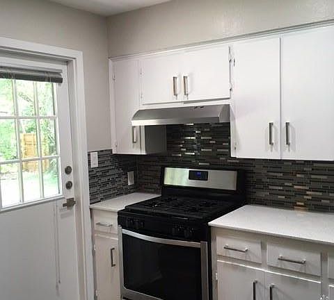 Kitchen is updated with stainless steel appliances, backsplash, recessed lighting and ceiling fan. Door goes to backyard.