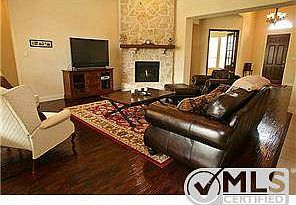 Living room with hand scraped wood floors and stone fireplace.