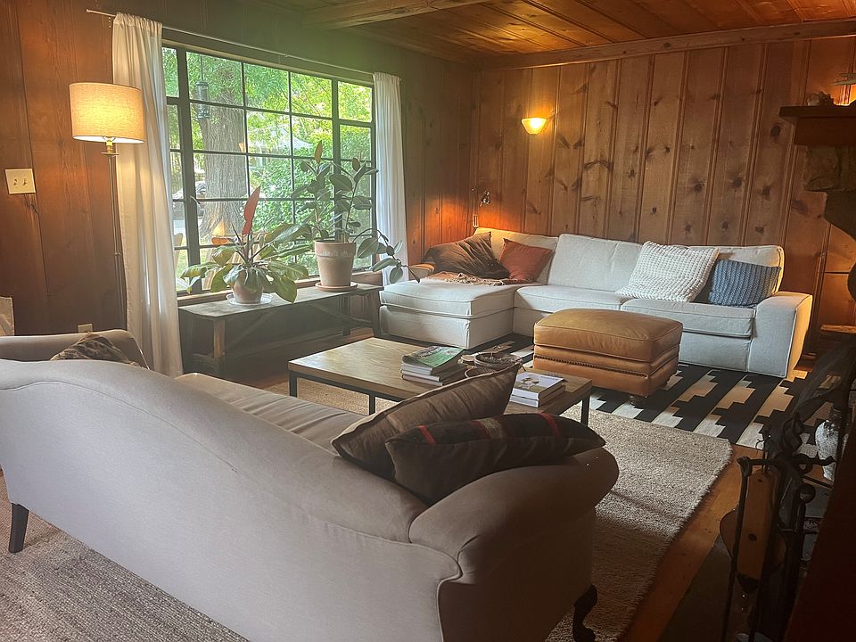 Living room with wall sconces, built-in bookshelf, picture window, and working fireplace.