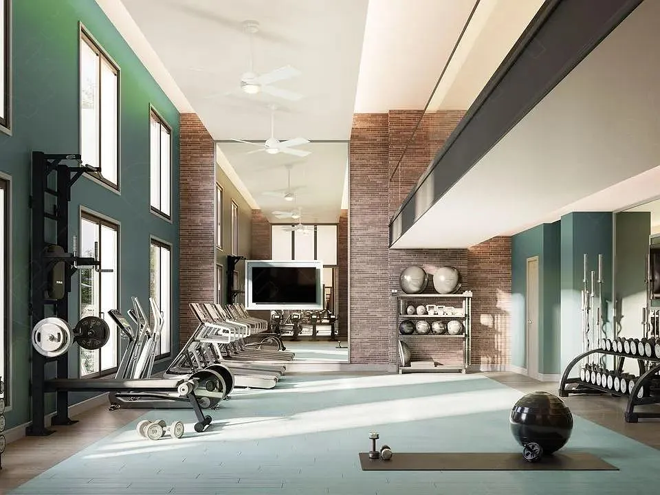 Double-height fitness center with strength and cardio equipment, expansive windows, and dedicated space for training, conditioning, and recovery.