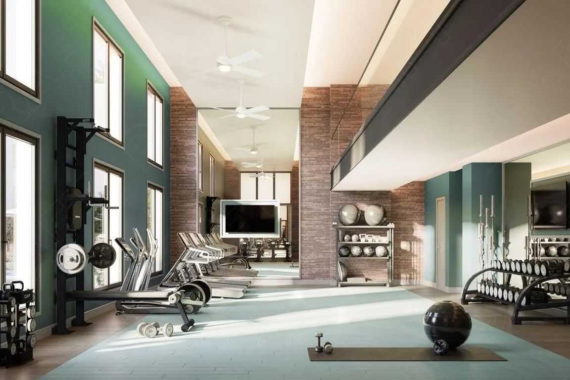 Double-height fitness center with strength and cardio equipment, expansive windows, and dedicated space for training, conditioning, and recovery.