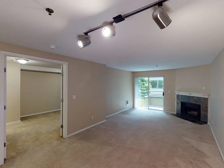 Apartment living room with plush carpet flooring, fireplace and balcony in select homes.