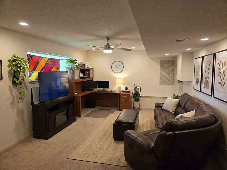 Comfortable PRIVATE living room with leather seating, large TV, and a built-in desk nook ideal for work or streaming.