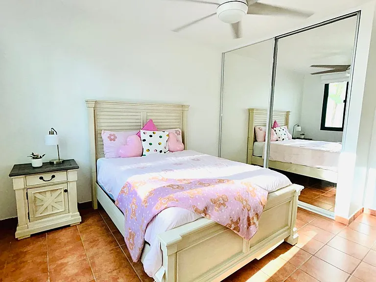 Spacious bedroom 1 featuring a ceiling fan, A/C system, blinds, closet, nightstand, bedside lamp, and its own private bathroom