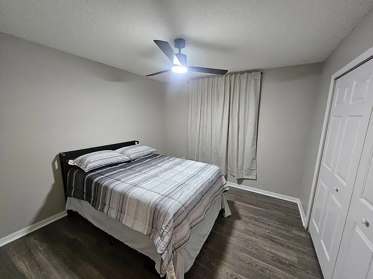 Private bedroom with a full-size bed, ceiling fan light, wood-look flooring, and a closet for convenient storage.