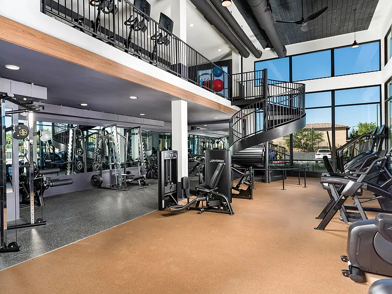 A spacious two-level fitness center at Modera Higley Commons, featuring expansive windows, advanced equipment, and room to train at your own pace.