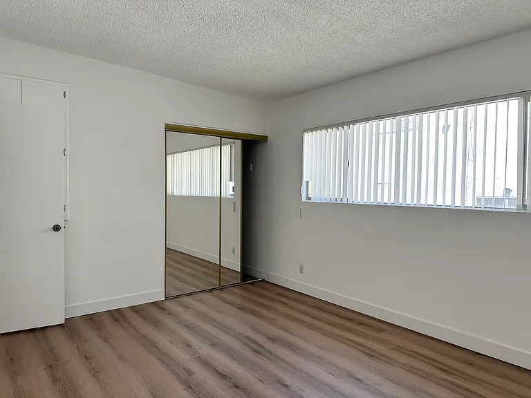 Primary bedroom with large window and mirrored closet