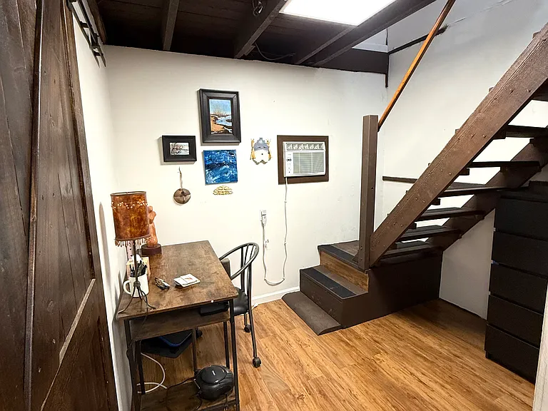 9.75x7.75 office and storage space. Wall-mounted AC unit keeps the space cozy. Desk included.
