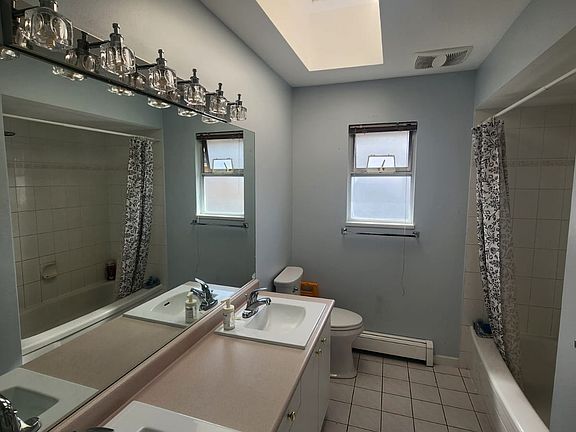 A full bathroom with two sinks. Modern lights. Well maintained.