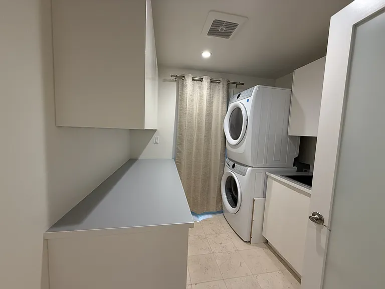 Convenient laundry room with full-size washer and dryer, including a laundry sink, lengthy countertop with built-in cabinets.