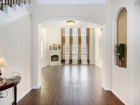 This is your first view of the living room from the entryway. It has soaring ceilings, a beautiful wall of windows, and a gas fireplace. Formal dining room is to your right.