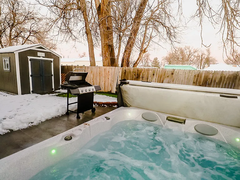 An inviting outdoor retreat boasting both a soothing Jacuzzi and a modern BBQ grill, perfect for relaxation and entertaining under the open sky
