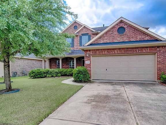 View of double driveway, 2-car garage entrance, shady oak trees in the front yard.