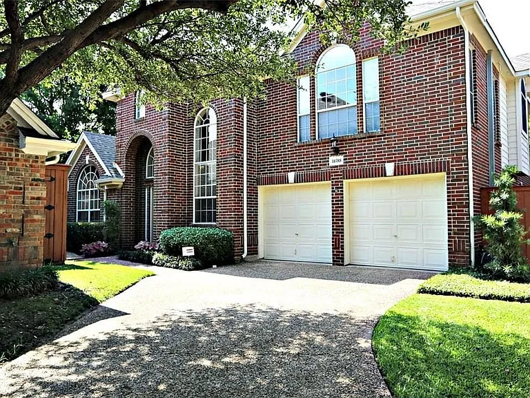 Brick two-story residence with a two-car garage, arched entryways, and upper-level arched windows