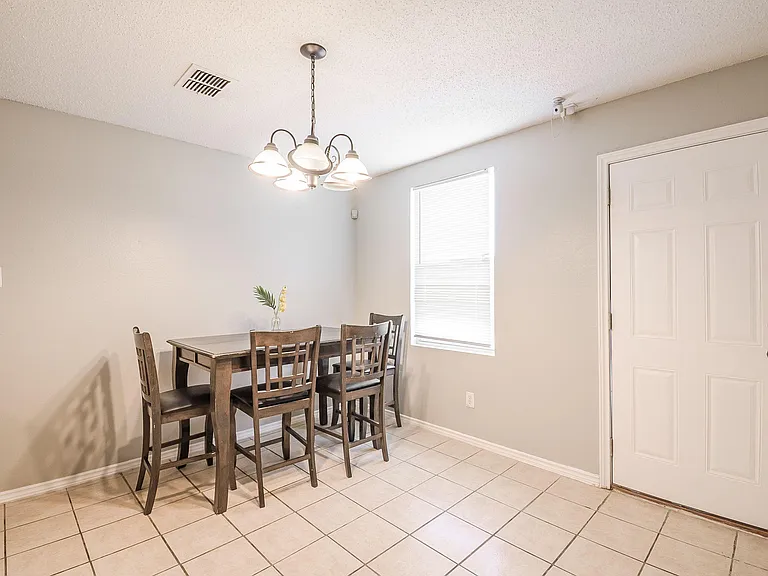 Dedicated dining area with tiled flooring, overhead chandelier, and a window for natural lightideal for shared meals.