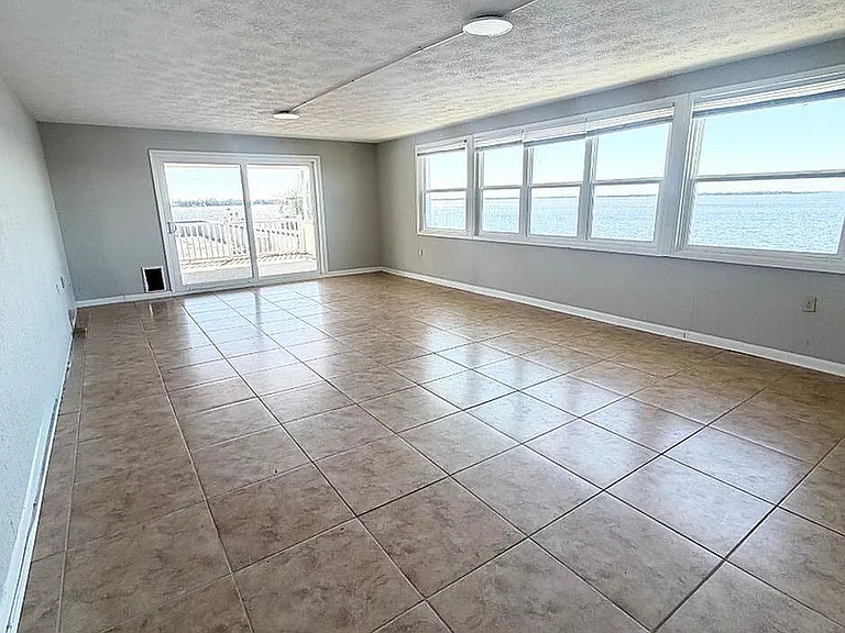 Expansive living space with tiled floors and large windows offering stunning waterfront views, perfect for a serene lifestyle.