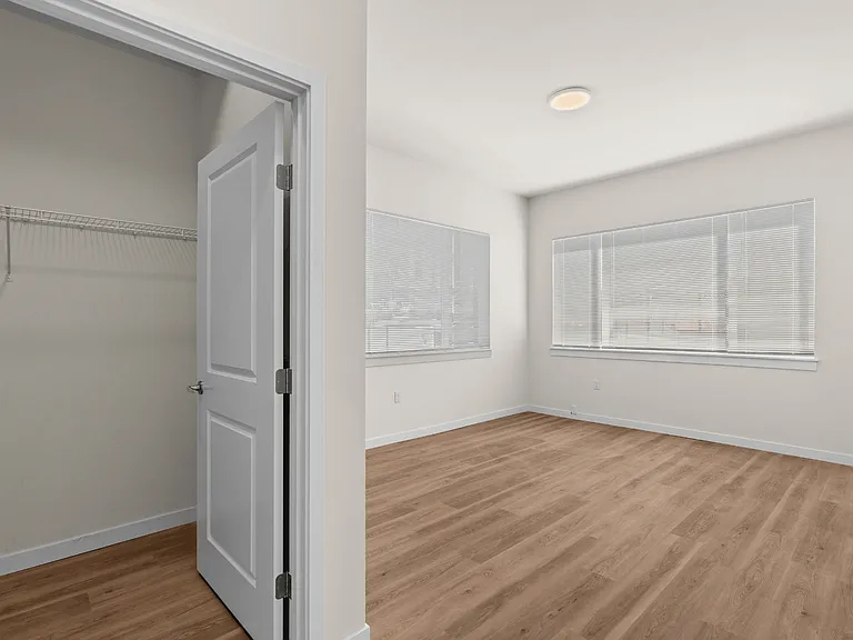 Spacious bedroom with a walk-in closet and large windows at 27 West Apartments.