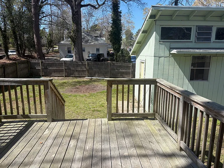 View of large fenced in backyard with porch and shed