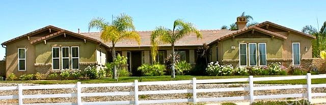 Front View from Street showing the mature roses and palms with inviting porch area