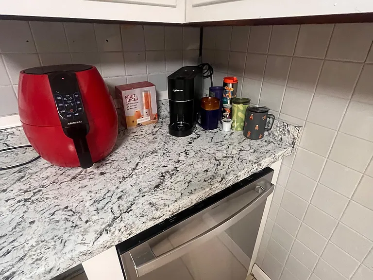 Kitchen countertop space with upper cabinetry, tile backsplash, and dishwasher for convenient everyday meal prep.