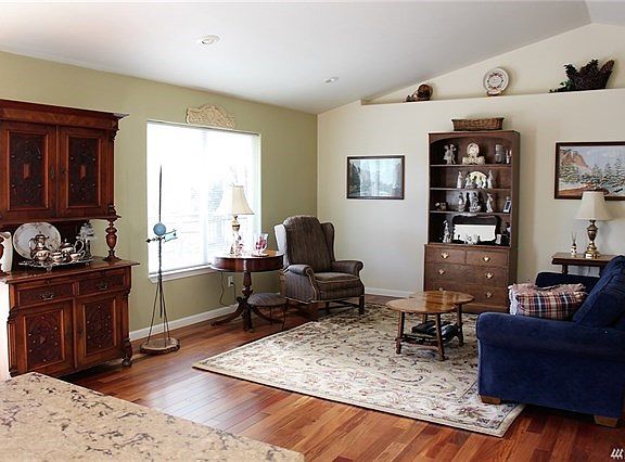 Beautiful vaulted great room with rich hardwood floors, open to kitchen and dining and flooded with light from large windows and sliding glass doors. hardwood extends down hallway.