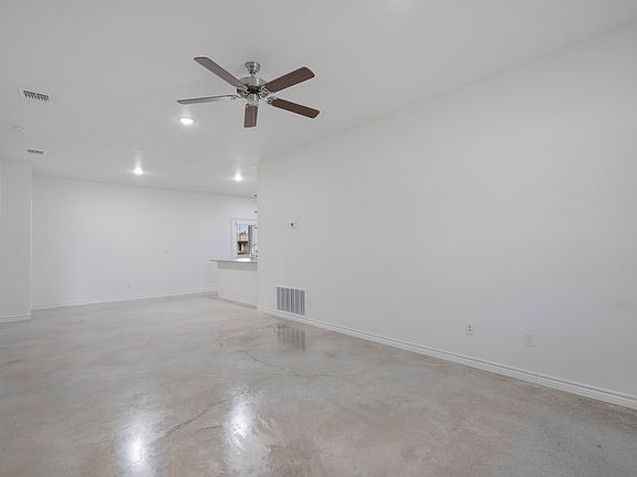 Long, open living space with natural light, neutral walls, and modern lighting. The open layout allows flexible furniture placement and a seamless flow throughout the home