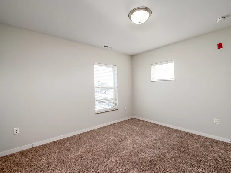 Bright and inviting bedroom with plush carpet, ample natural light, and modern ceiling light fixture. Bright and inviting bedroom with plush carpet, ample natural light, and modern ceiling light fixture.