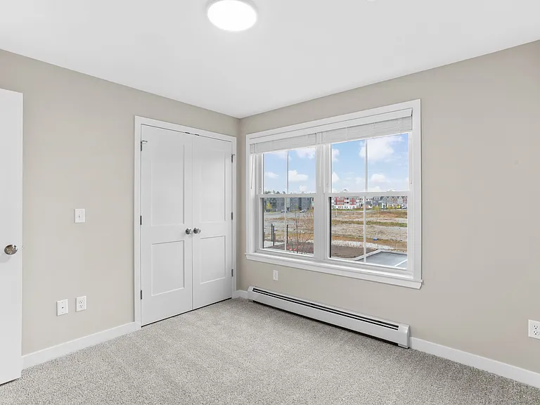 Spacious bedroom with plush carpeting, generous closet space, and natural light from a large window.