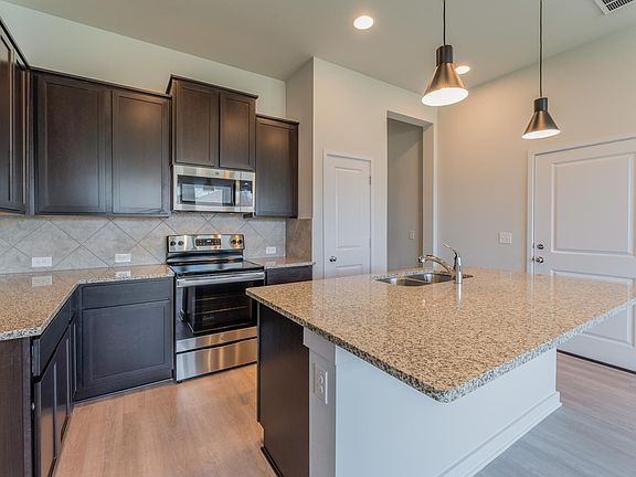 Bright spacious open kitchen with granite countertop serving as a breakfast bar, lot of cabinets, large pantry, stainless steel fixtures and refrigerator
