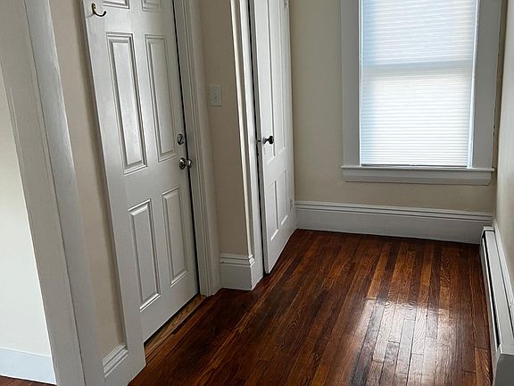 Hallway -- living room access on near left, front door in the middle, closet door far left, kitchen is down hall to the right. Window overlooks a lawn/garden